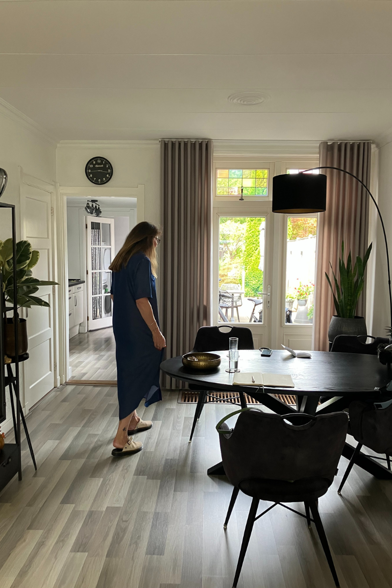 Comfortabele, geïsoleerde woonkamer met veel lichtinval door dubbele deuren naar de tuin, vrouw loopt door de ruimte.